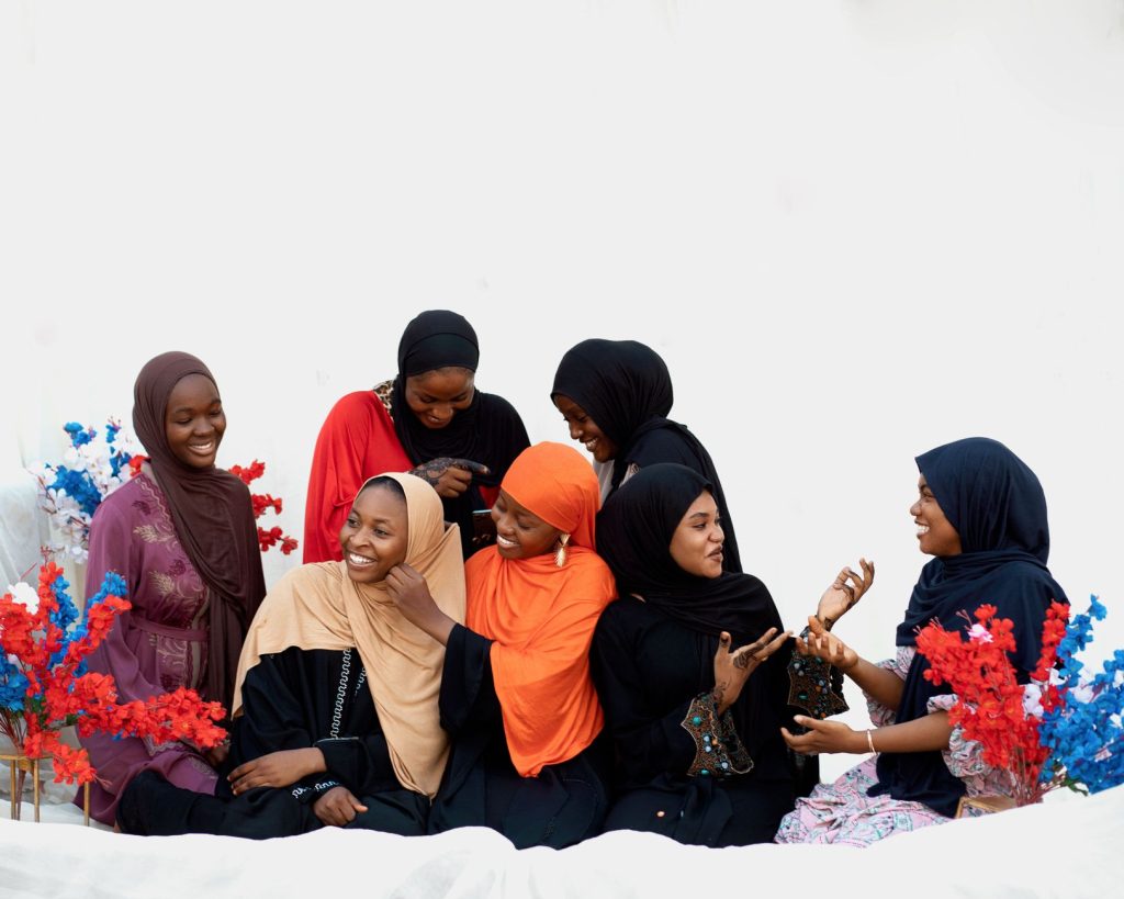 A group of women in colorful hijabs enjoying a cheerful group interaction, showcasing unity and diversity. — Ambiiyah