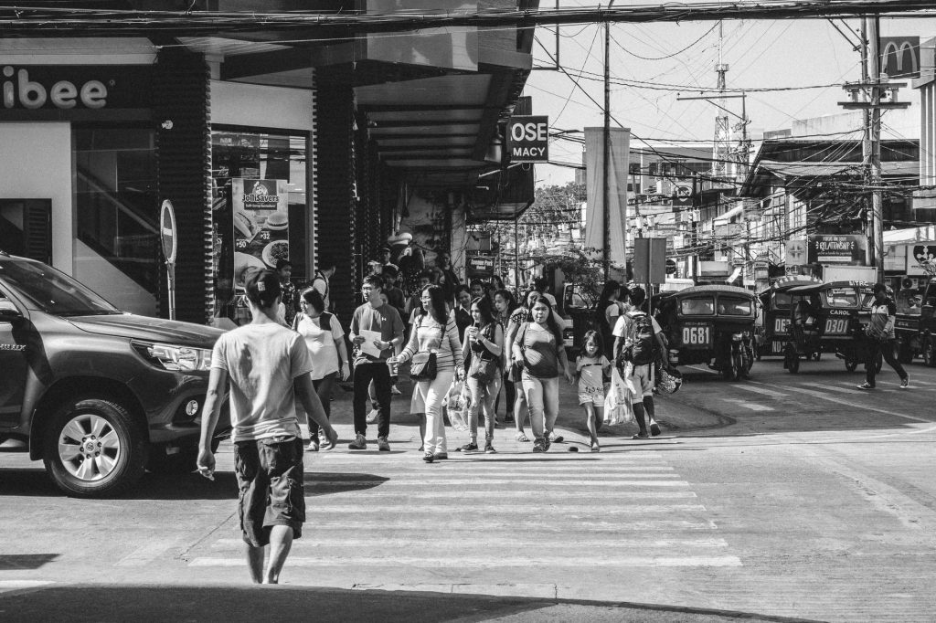 Pedestrians crossing a street in Dumaguete City, a bustling urban scene captured in black and white. — Ano Ang