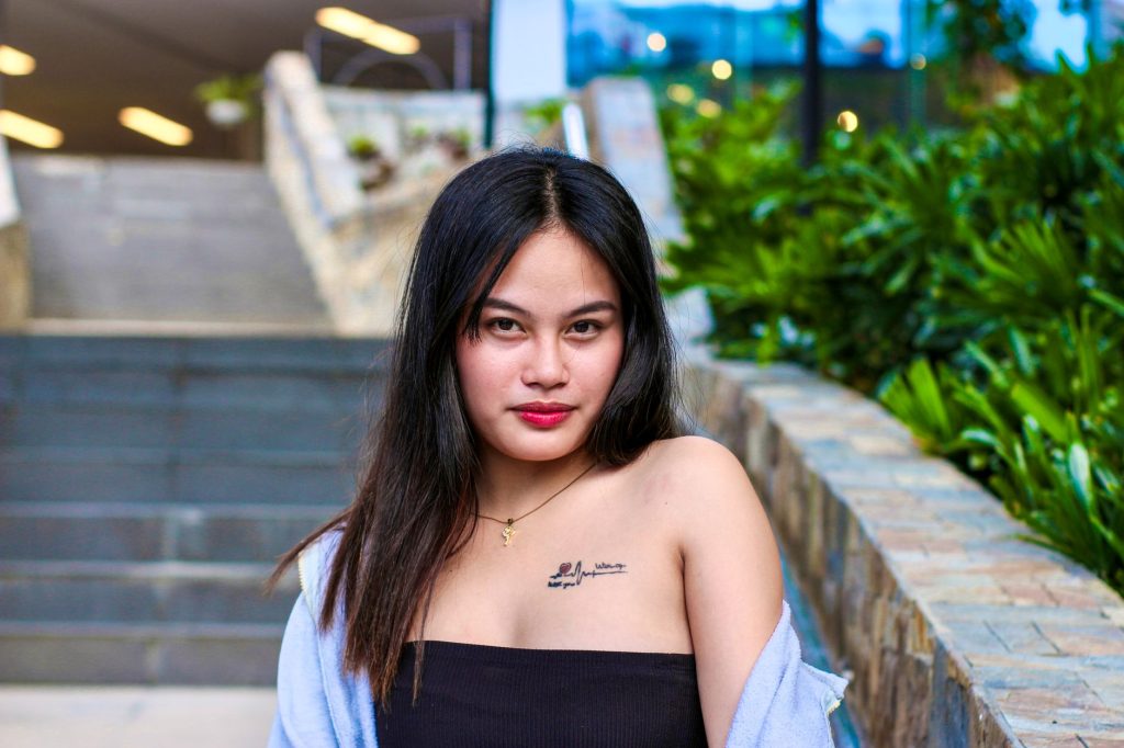 Woman with tattoo poses confidently outdoors on urban steps. — Asian Pinay