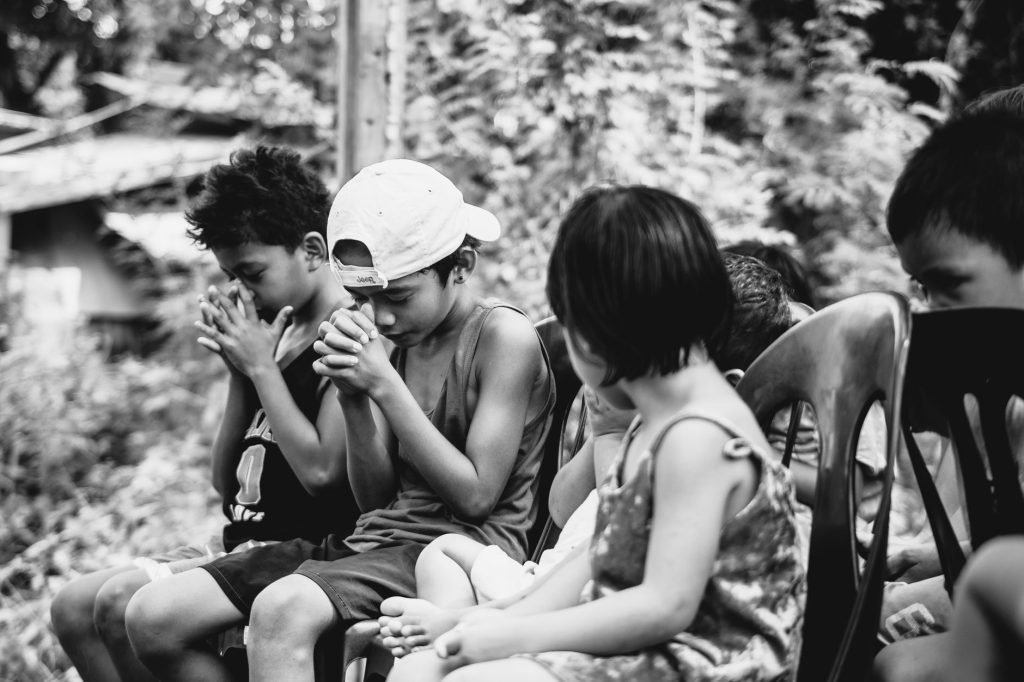 A touching black and white image of children sitting together in prayer. — Bakit