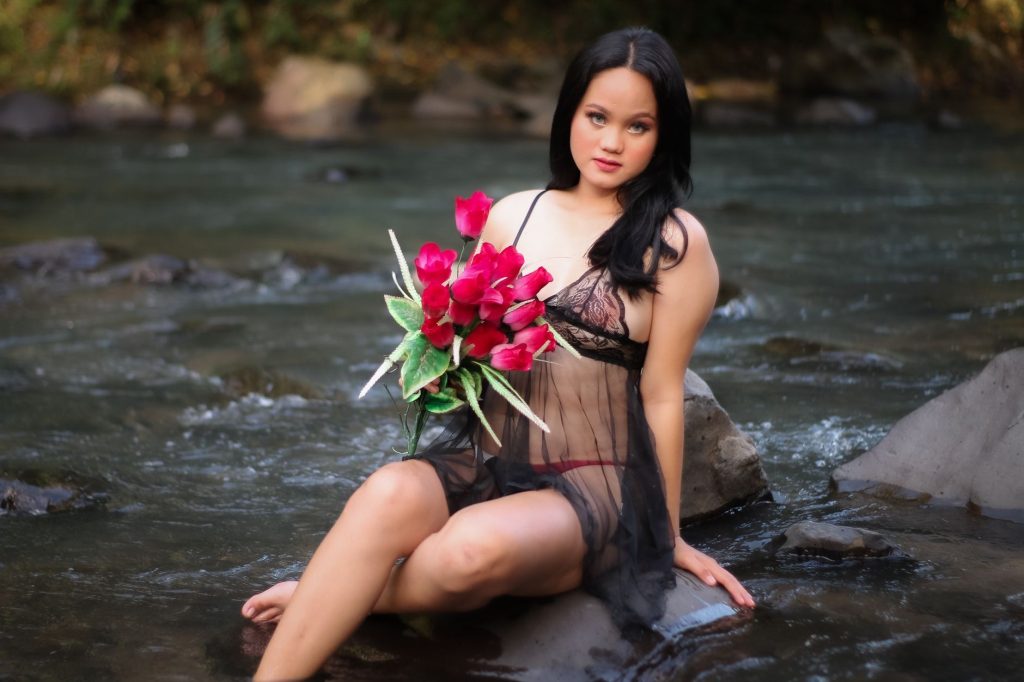 A woman in lingerie poses with a bouquet beside a tranquil river in Bulan, Philippines. — Hot Pinay