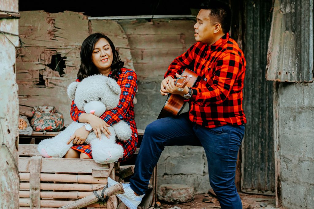 A couple enjoys a musical moment together outdoors, with a guitar and a teddy bear. — Ikaw At Ako Lyrics