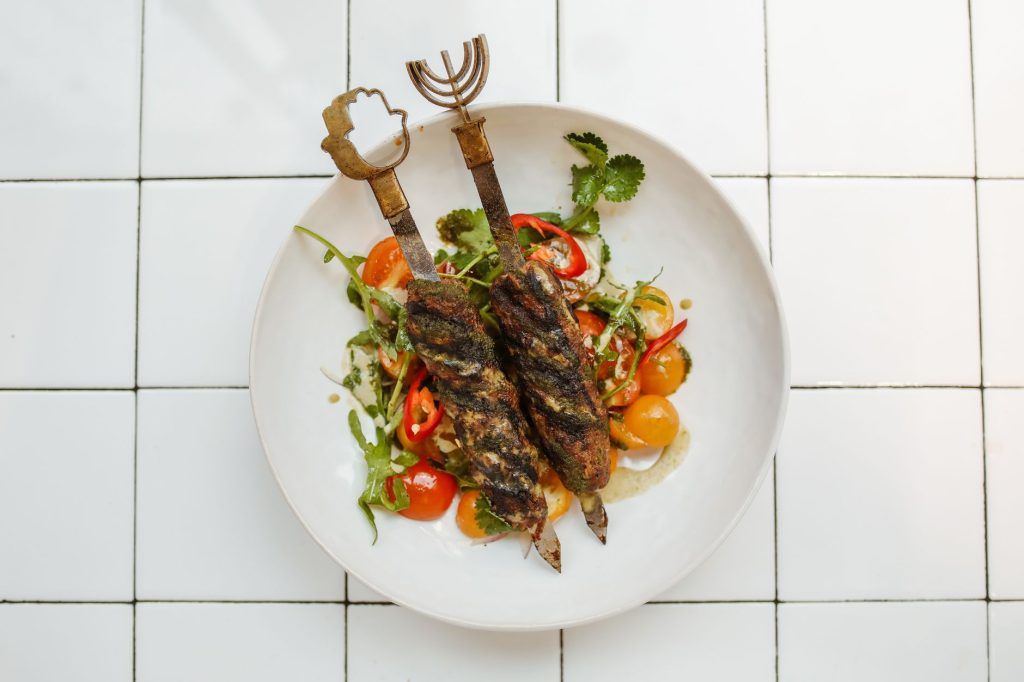 Grilled kebabs served on a fresh salad with vibrant vegetables, perfect for a gourmet meal. — Iyot