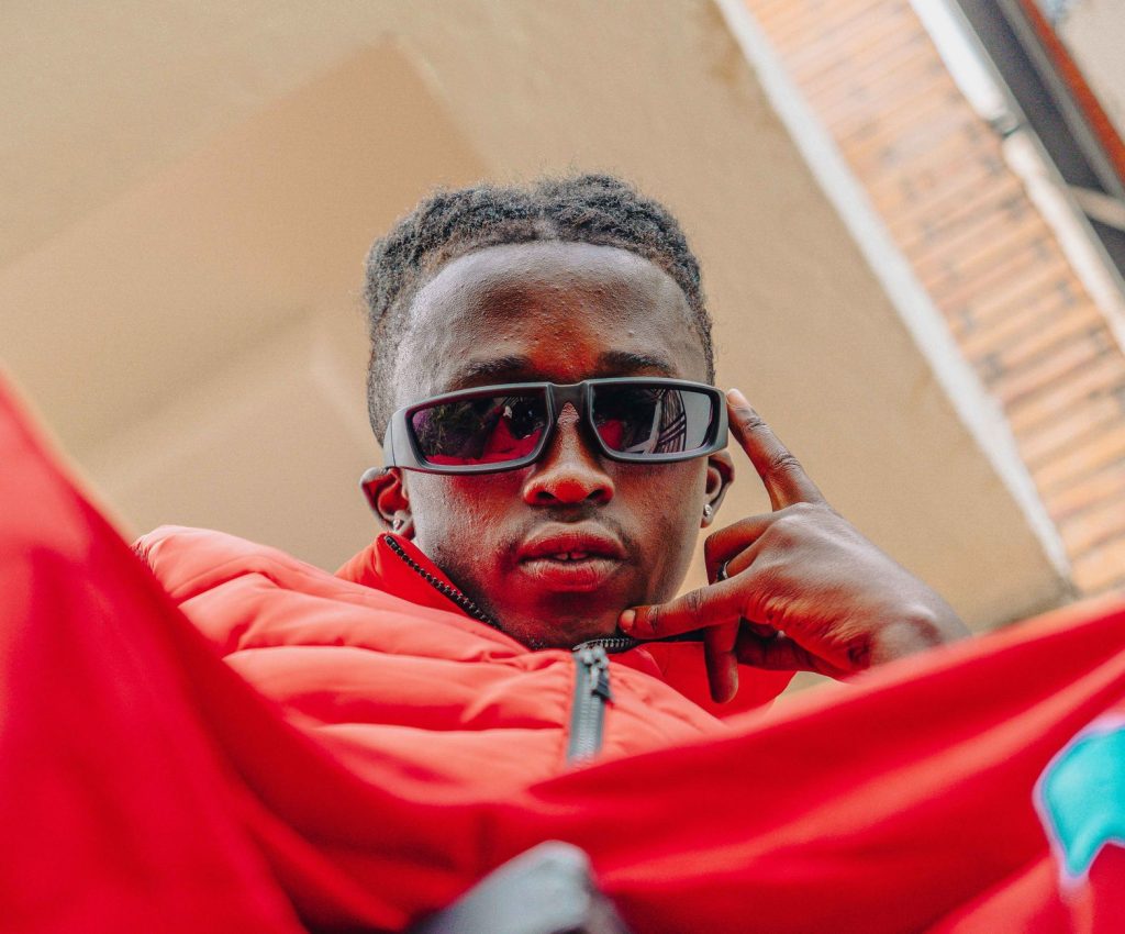 Fashionable young man in a red jacket posing with sunglasses in an urban setting. — Iyotube