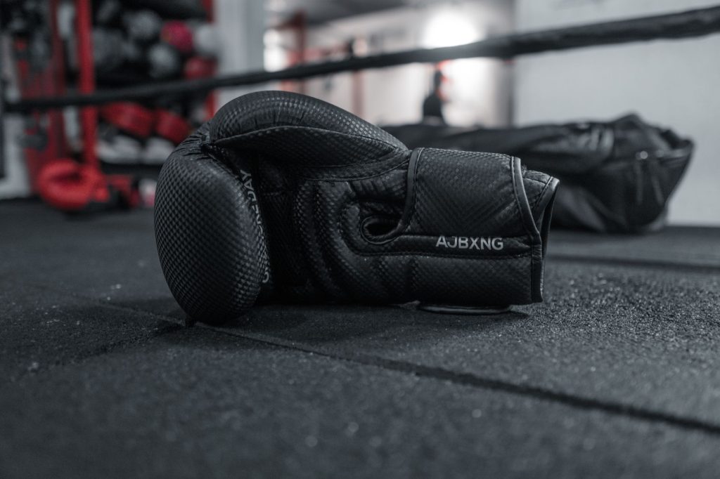 A close-up of a single black boxing glove lying on the gym floor, conveying a sense of resilience. — Jabplay