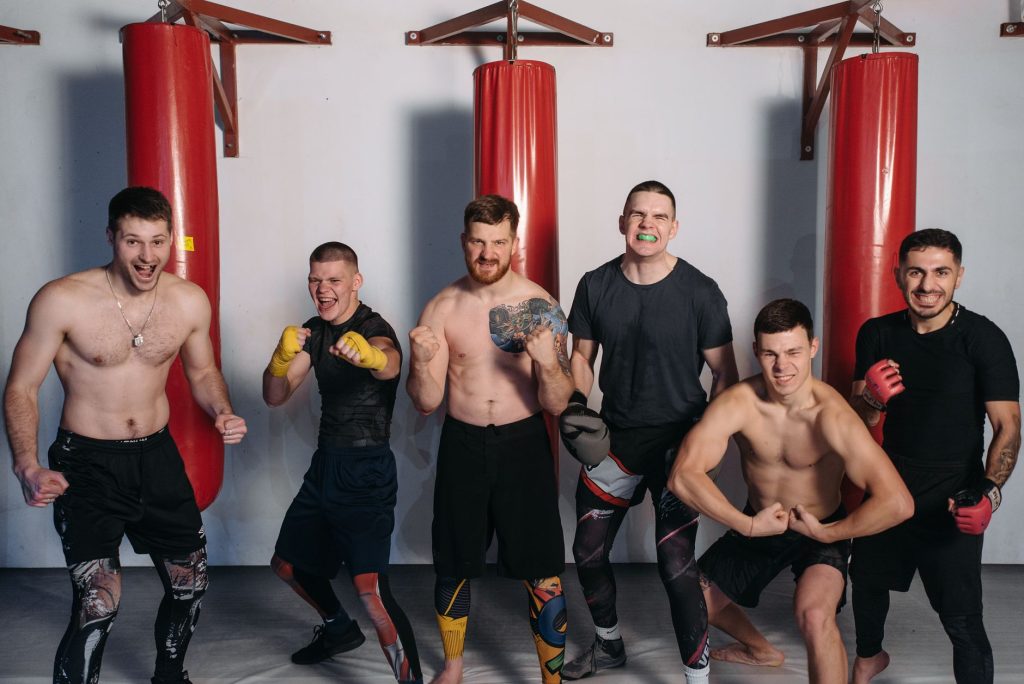 Six muscular men posing confidently in a gym, showcasing fighting spirit and camaraderie. — Jabplay
