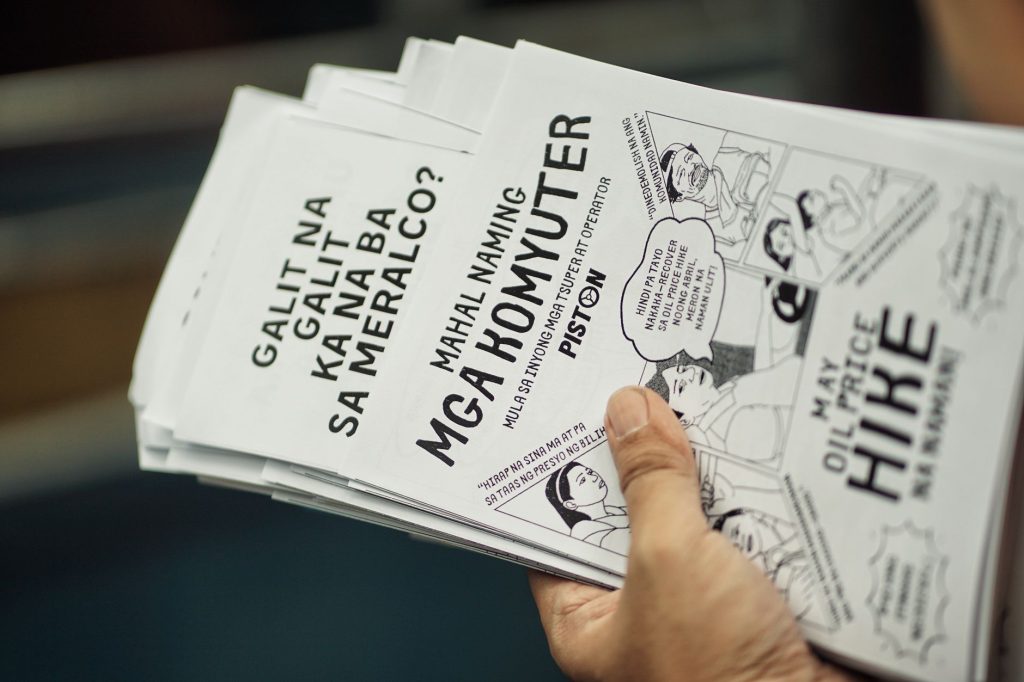A stack of protest flyers in a hand, highlighting social issues and community concerns. — Japanese To Tagalog
