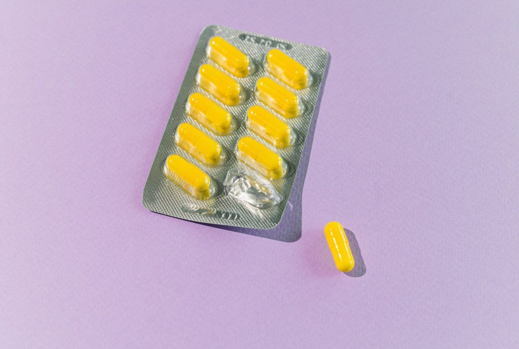 A blister pack of yellow capsules with one pill on a purple backdrop. — Kantotin