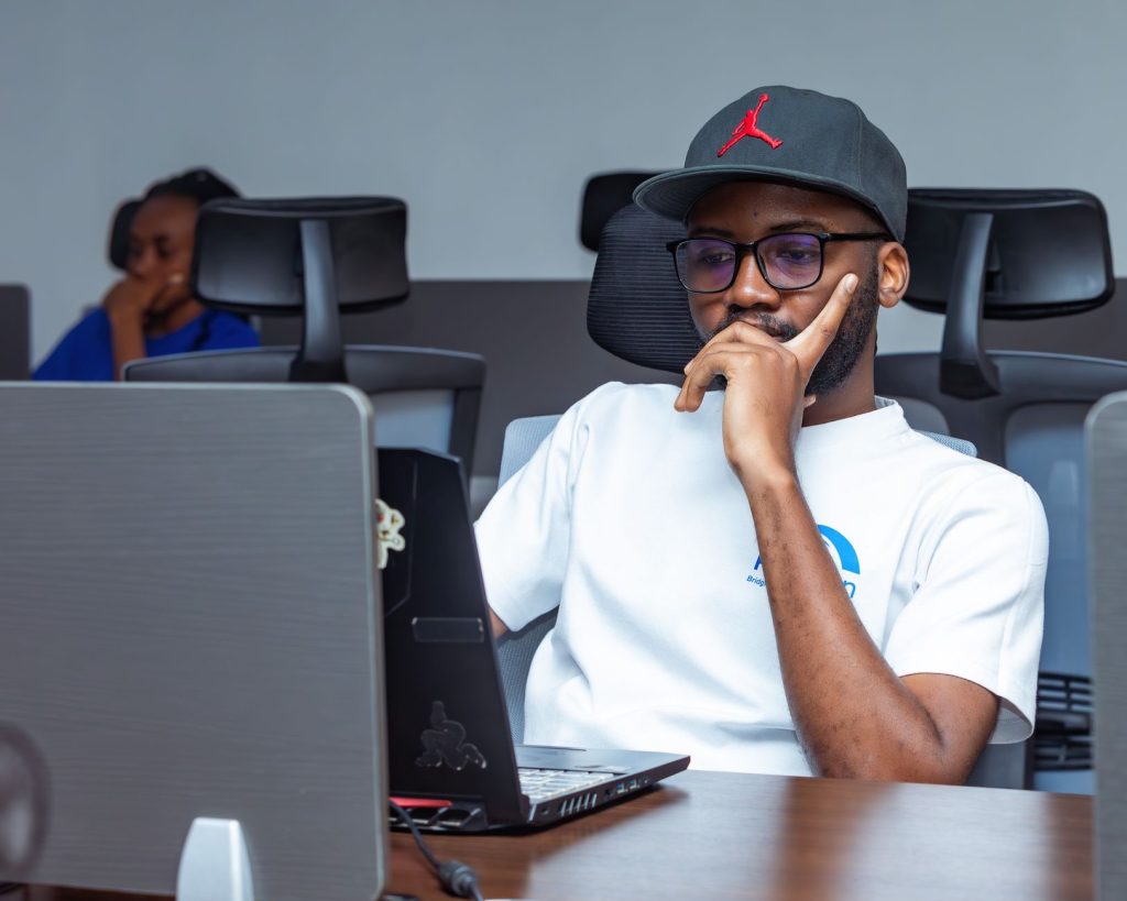 Young professional working intently on a laptop in a modern office setting. Ideal for business themes. — Kaplog