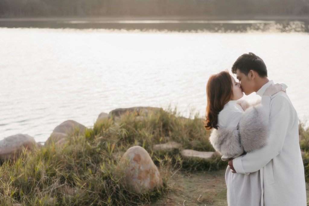 A romantic couple embracing by a serene lakeside at sunset, capturing love and intimacy. — Kiss Kh
