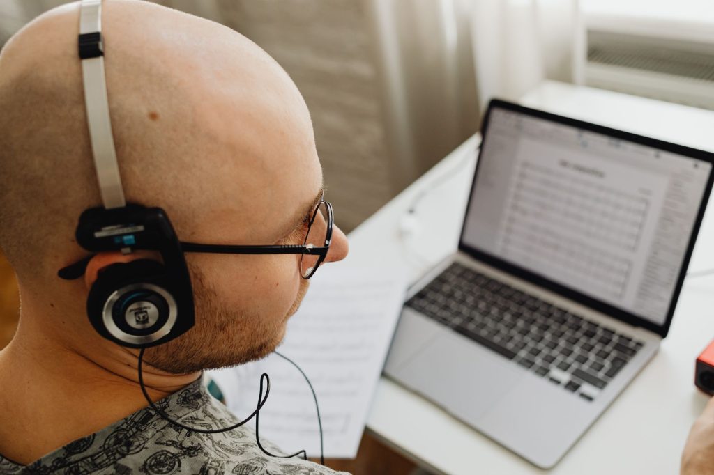 Bald man in headphones working on a laptop, focused on tasks. — Kisskh