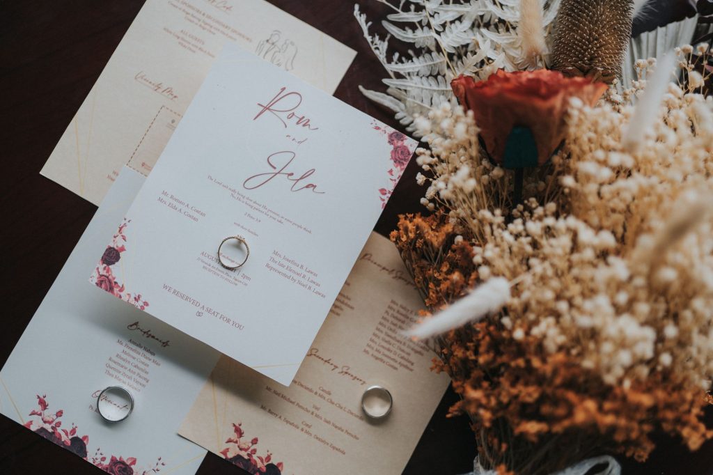 Beautifully designed wedding invitations paired with a rustic bouquet for a natural touch. — Liham