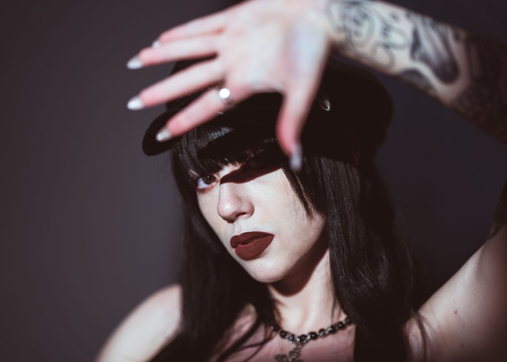 Artistic portrait of a young woman with tattoos, wearing dark lipstick and a stylish hat. — Lixe Lore