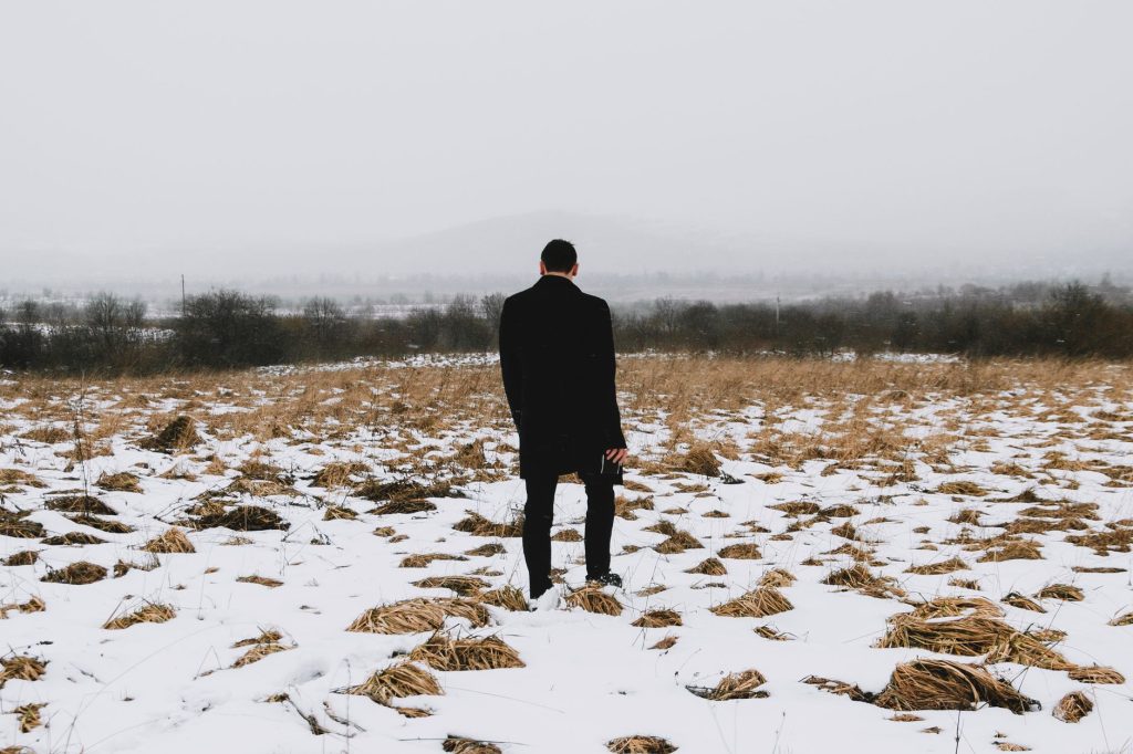 A man stands solitary in a snowy field in Ukraine, capturing a moment of winter solitude. — Love Is Gone Lyrics