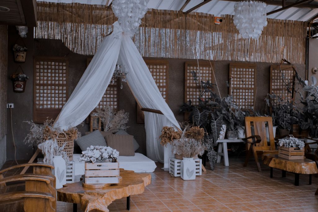 Elegant outdoor lounge area featuring rustic wooden furniture, white drapes, and lush plant decorations. — Lpb Piso Wifi
