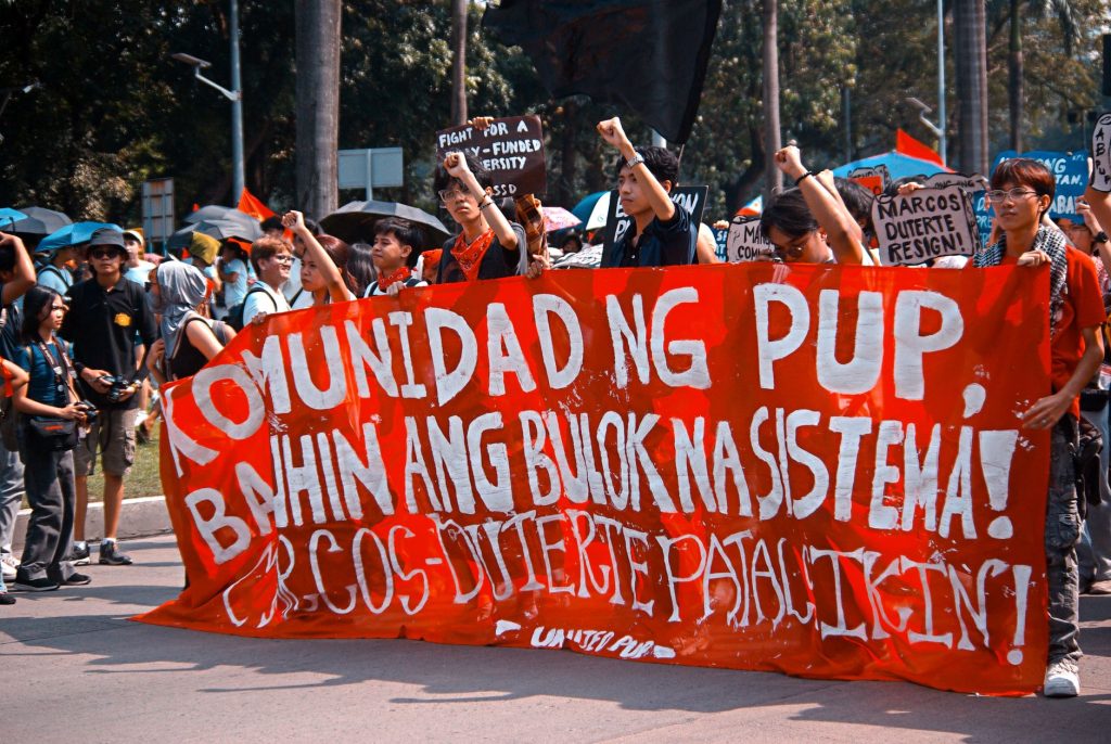 Demonstration in Manila advocating systemic change. Engaged crowd holding banners and signs. — Manila Exposed