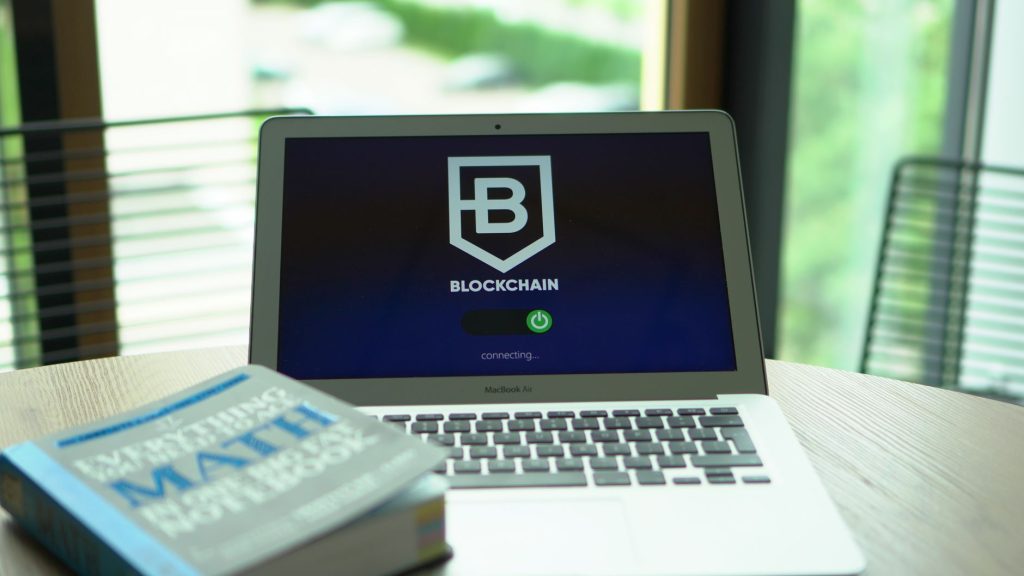 A laptop displays a blockchain screen next to a math textbook, symbolizing digital finance and education. — Mbc2030 Live Logi