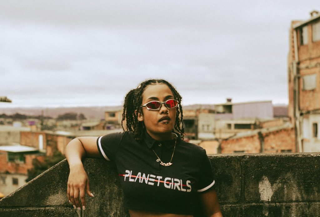 Confident woman with red shades on a São Paulo rooftop exuding urban style and attitude. — Mundo Lyrics