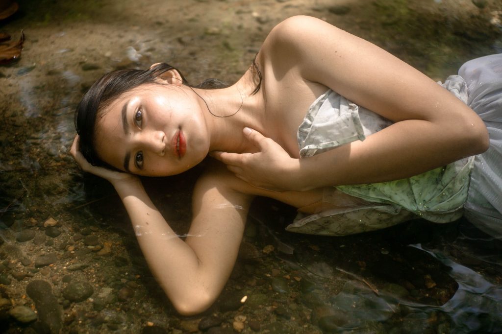 From above of tranquil female in dress with bare shoulders lying gracefully in water — Ng At Nang