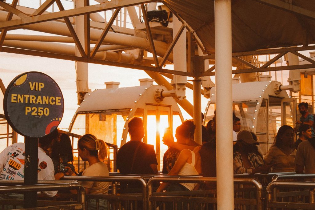 Tourists queuing for a ferris wheel ride at sunset with VIP entrance sign. — Pasigpass