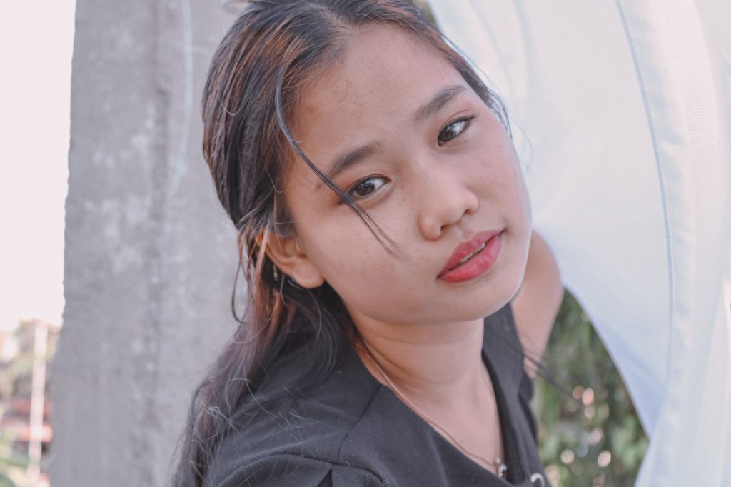 A young woman stands outdoors, drying fabric under natural daylight. Captured with Canon EOS 1500D. — Pinayfkix
