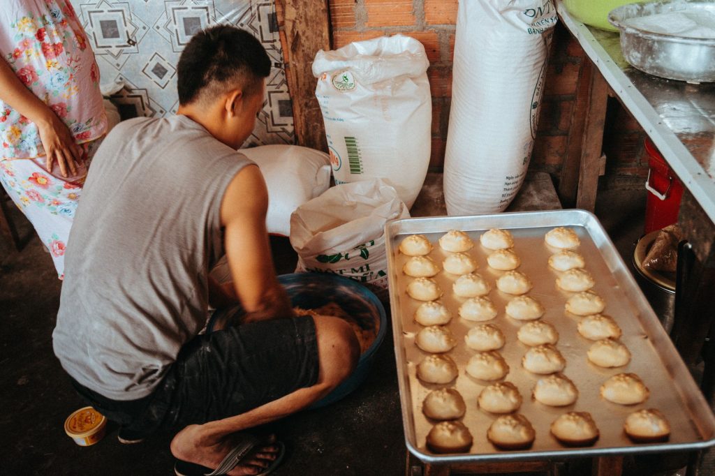 A man prepares traditional Vietnamese baked goods in a kitchen setting, showcasing cultural cuisine. — Pinayot