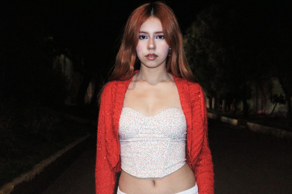 Portrait of a young woman in a red cardigan under night skies, outdoors. — Pinaysex