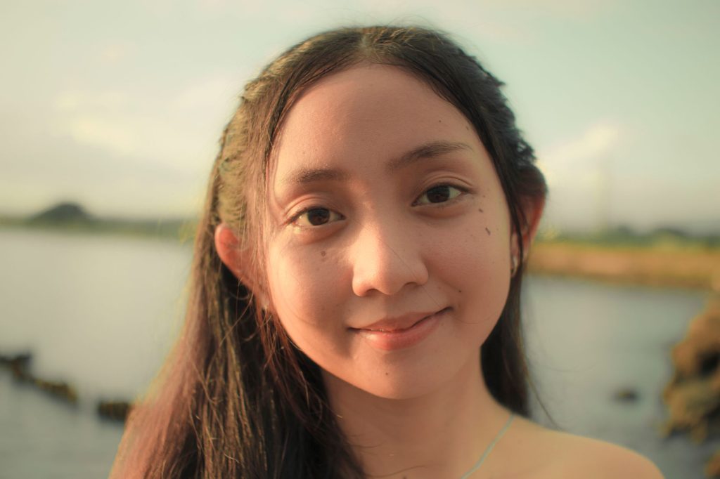 Portrait of a young woman smiling outdoors by the water, capturing natural beauty. — Pinaysex Com