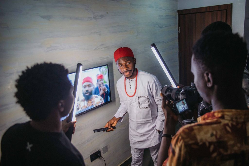 A group of men filming a video indoors with lighting equipment and a monitor. — Pinflix