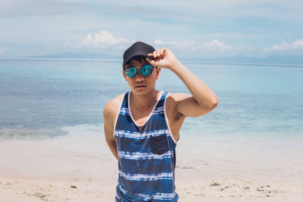Young man in casual attire enjoying a sunny day at a tropical beach with clear blue waters. — Pinoysex