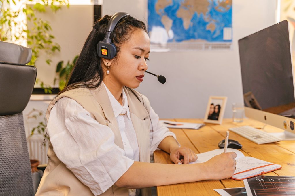 Businesswoman in an office environment wearing a headset and writing notes. — Pronhub