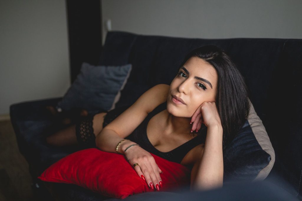 A young woman in black lingerie lying on a couch looking at the camera with a relaxed expression. — Purnhub