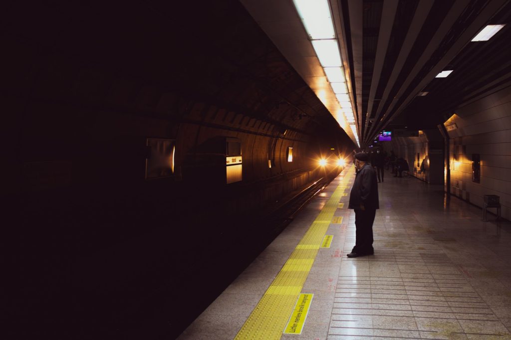 A person waits on a subway platform in Istanbul as a train approaches in the dimly lit station. — Sarapbeh