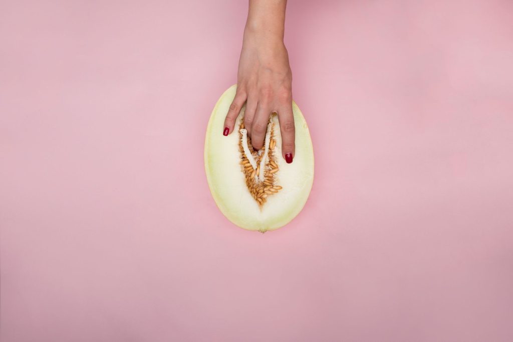 Artistic expression with hand touching a melon, resembling modern conceptual symbolism on a pink backdrop. — Sex Vedio