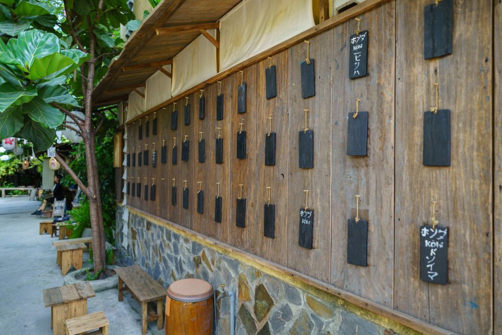 A rustic wooden wall with hanging message boards in a serene outdoor setting, exuding traditional charm. — Tagalog To Japanes