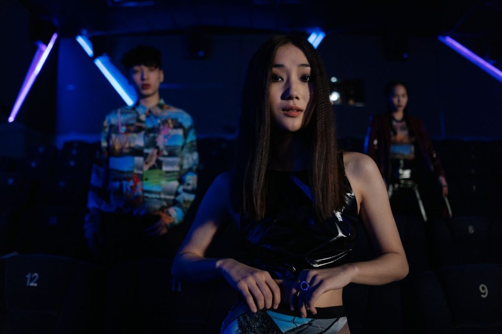 Fashionable young adults posing in a dimly lit, modern theater with neon lighting. — Taya Full Movie