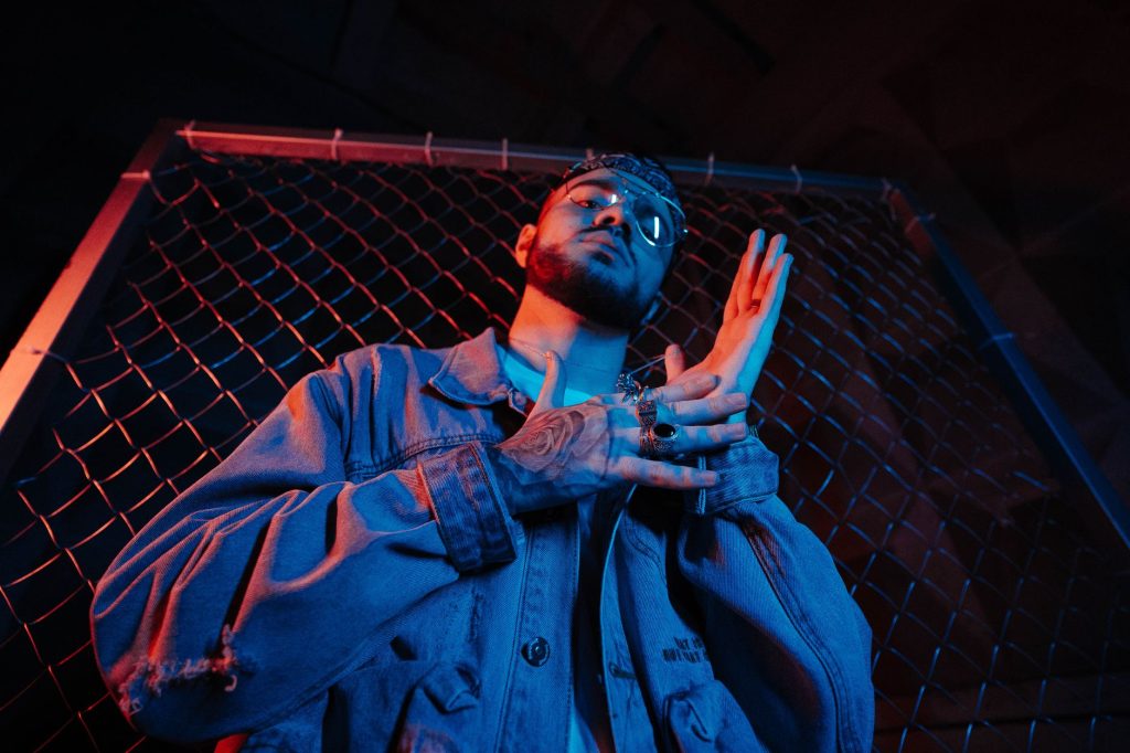 Portrait of a stylish man posing in blue lighting, featuring a cool and introspective fashion shoot. — To The Bone Lyrics