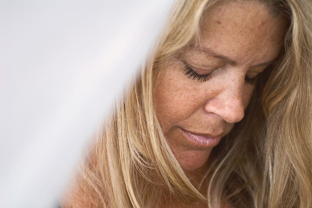 Close-up portrait capturing the serene expression of a blonde woman in a moment of quiet contemplation. — Toni Fowler