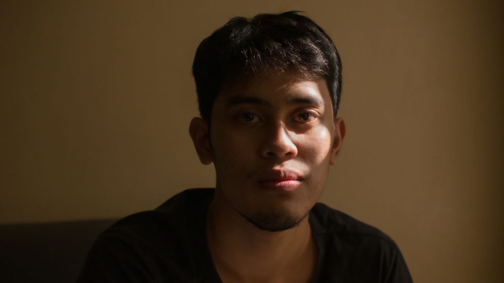 Face of young handsome ethnic male in apartment on dark yellow background in bright sunlight — Wally Bayola Scandal