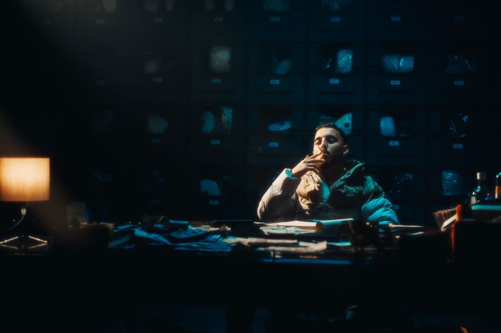 A contemplative man sits smoking in a dimly lit room, adding mystery and ambiance. — Weakness Lyrics