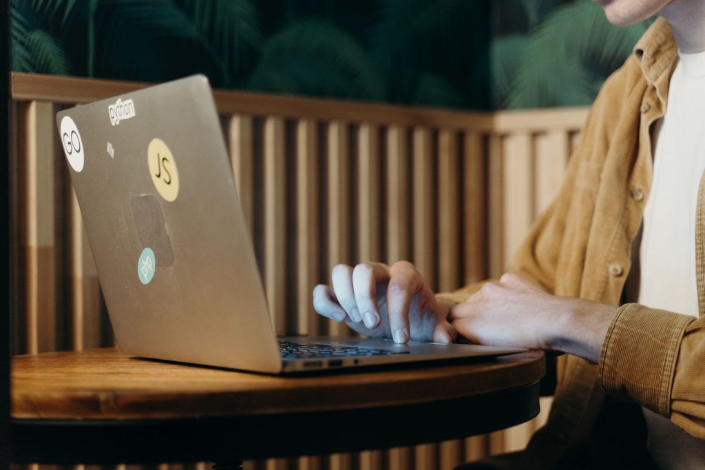 Person typing on a laptop in a cozy café, surrounded by greenery, enhancing focus and productivity. — Weth To Php