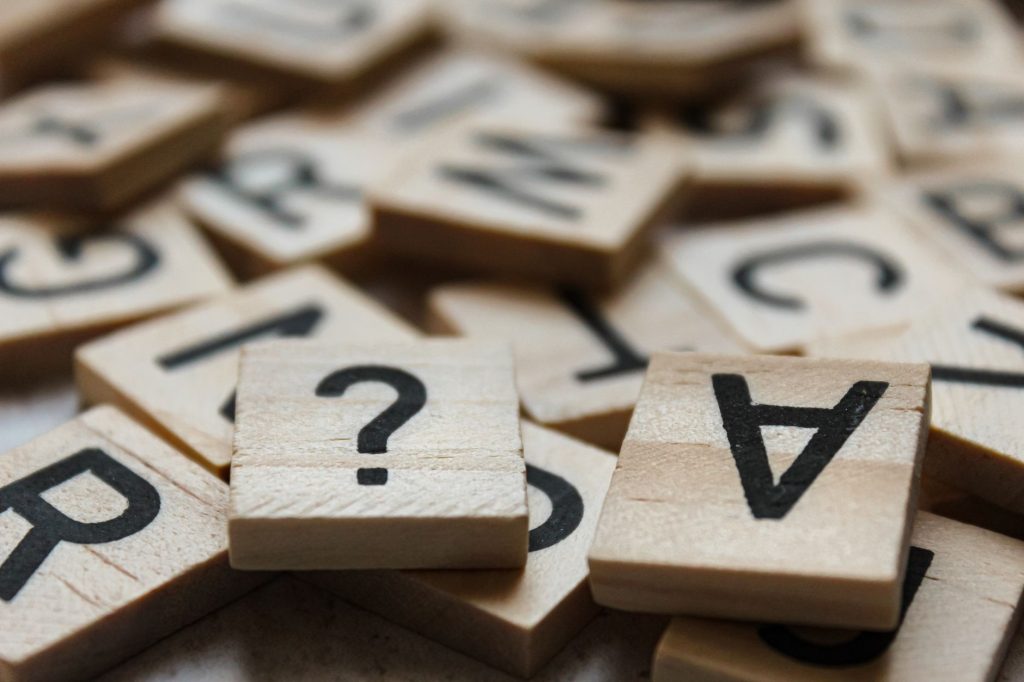 Close-up of wooden Scrabble tiles with letters and symbols, focusing on creativity and language. — Which Of The Following