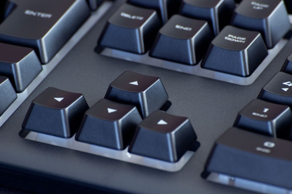 Detailed close-up of a black computer keyboard's arrow keys, highlighting the sleek design. — Xbree
