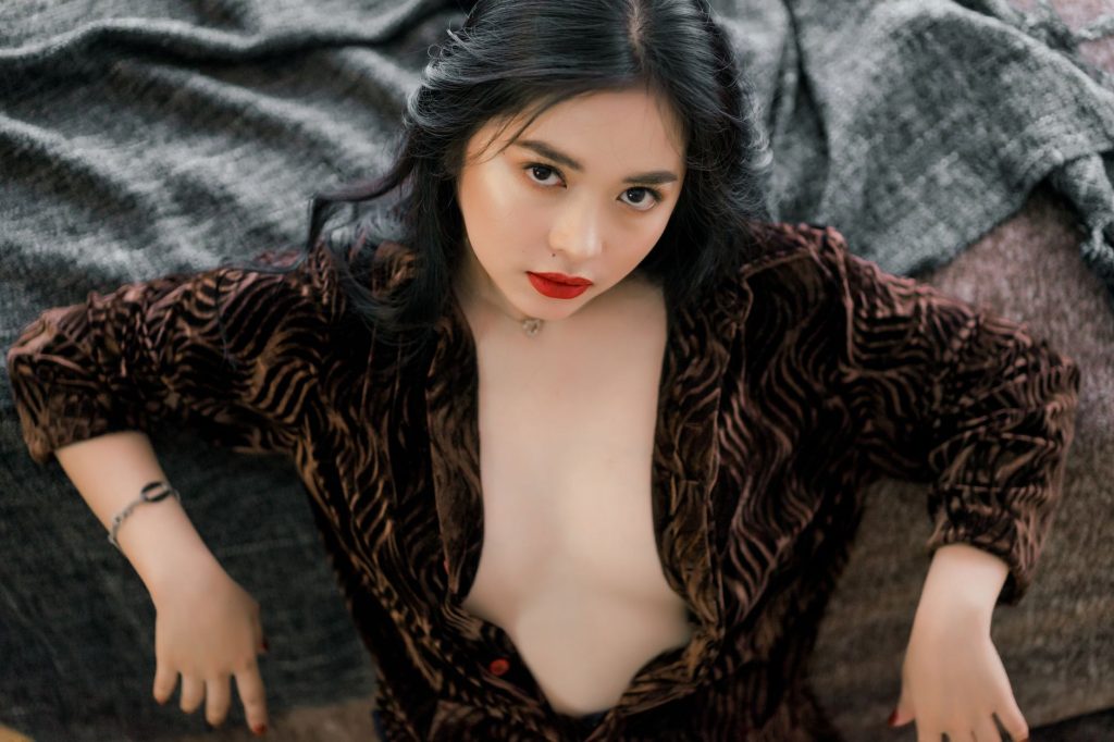 High-angle shot of an elegant woman in a brown velvet outfit, red lips, looking intently. — Xmxx