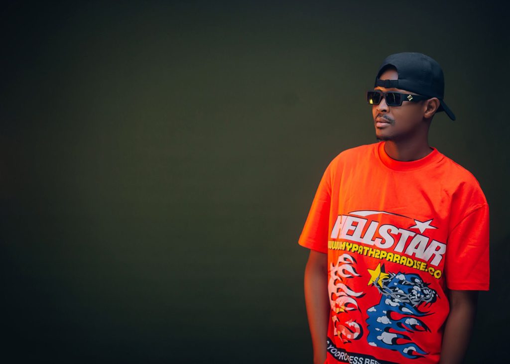Fashionable man wearing sunglasses and a bold graphic t-shirt against a solid background. — Ymp3