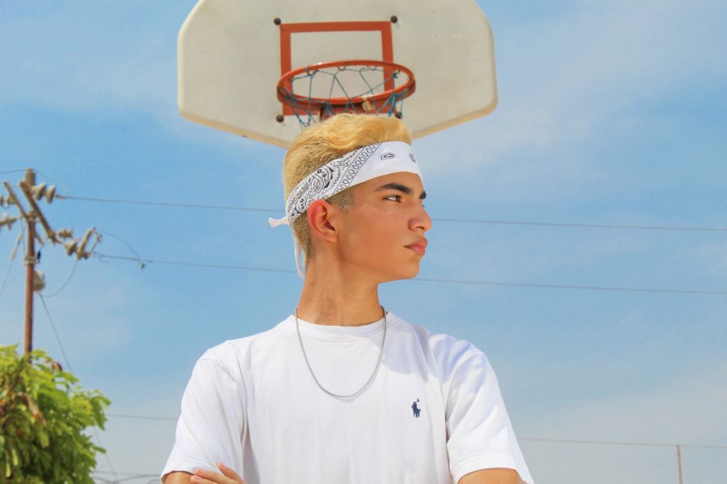 Confident young man with bandana standing near a basketball hoop on a sunny day. — Youjezz