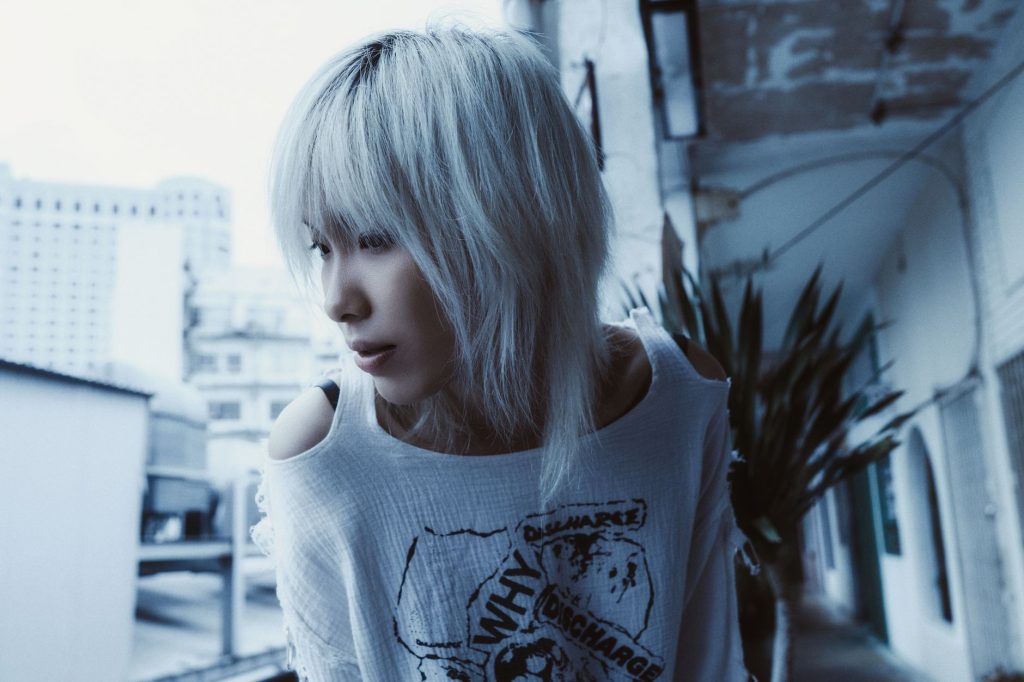Stylish portrait of a person with platinum hair in an urban setting, captured in cool tones. — Yuo